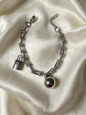 Silver-tone chain link charm bracelet with ball and padlock charms